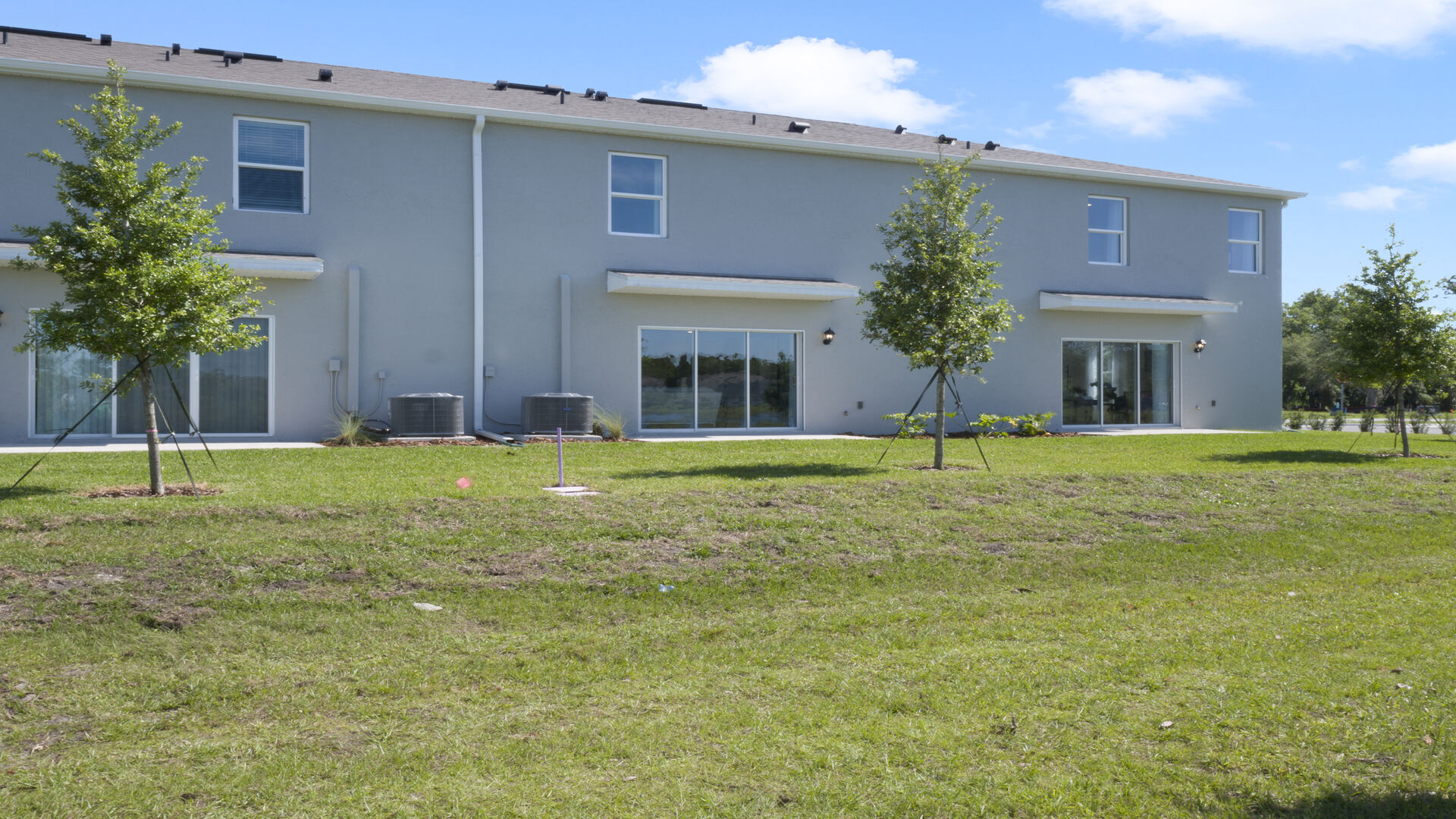 Rear of home with view of grassed backyard, porch seating and slider glass doors.