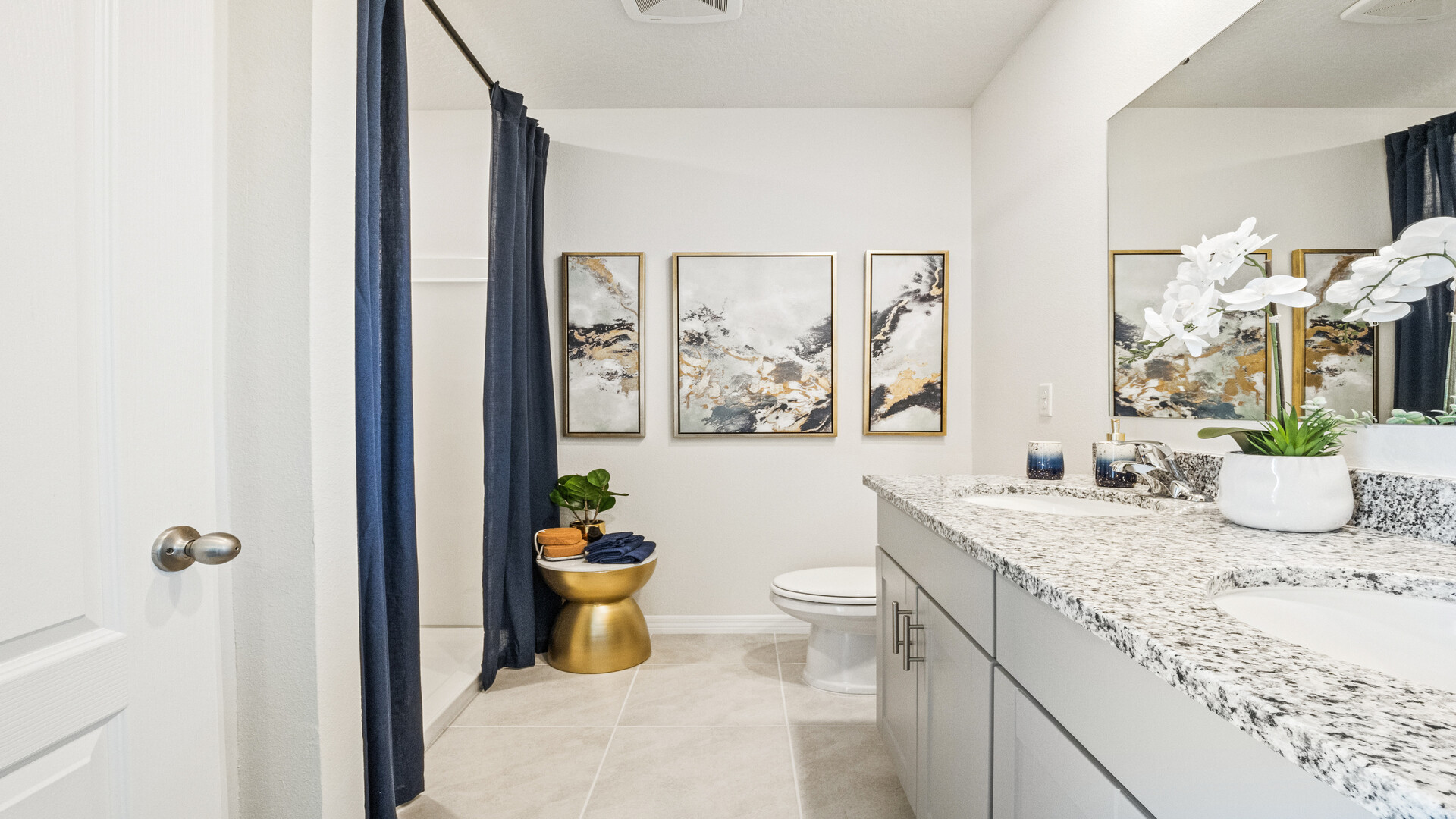 Modern bathroom with double vanity sinks, large wall mirror, cabinets and granite countertops.