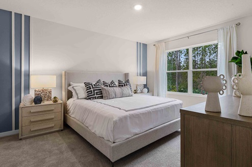 Spacious primary bedroom with king size bed, carpet flooring, natural lighting and a walk in closet.