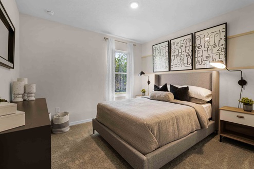 Spacious primary bedroom with king size bed, carpet flooring, natural lighting and a walk in closet.