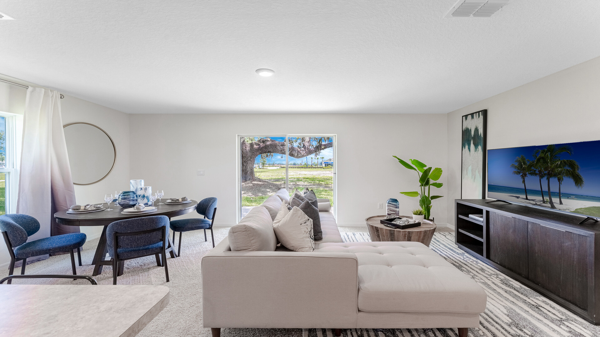 Open concept living area with couch seating and access to the backyard thru slider door.
