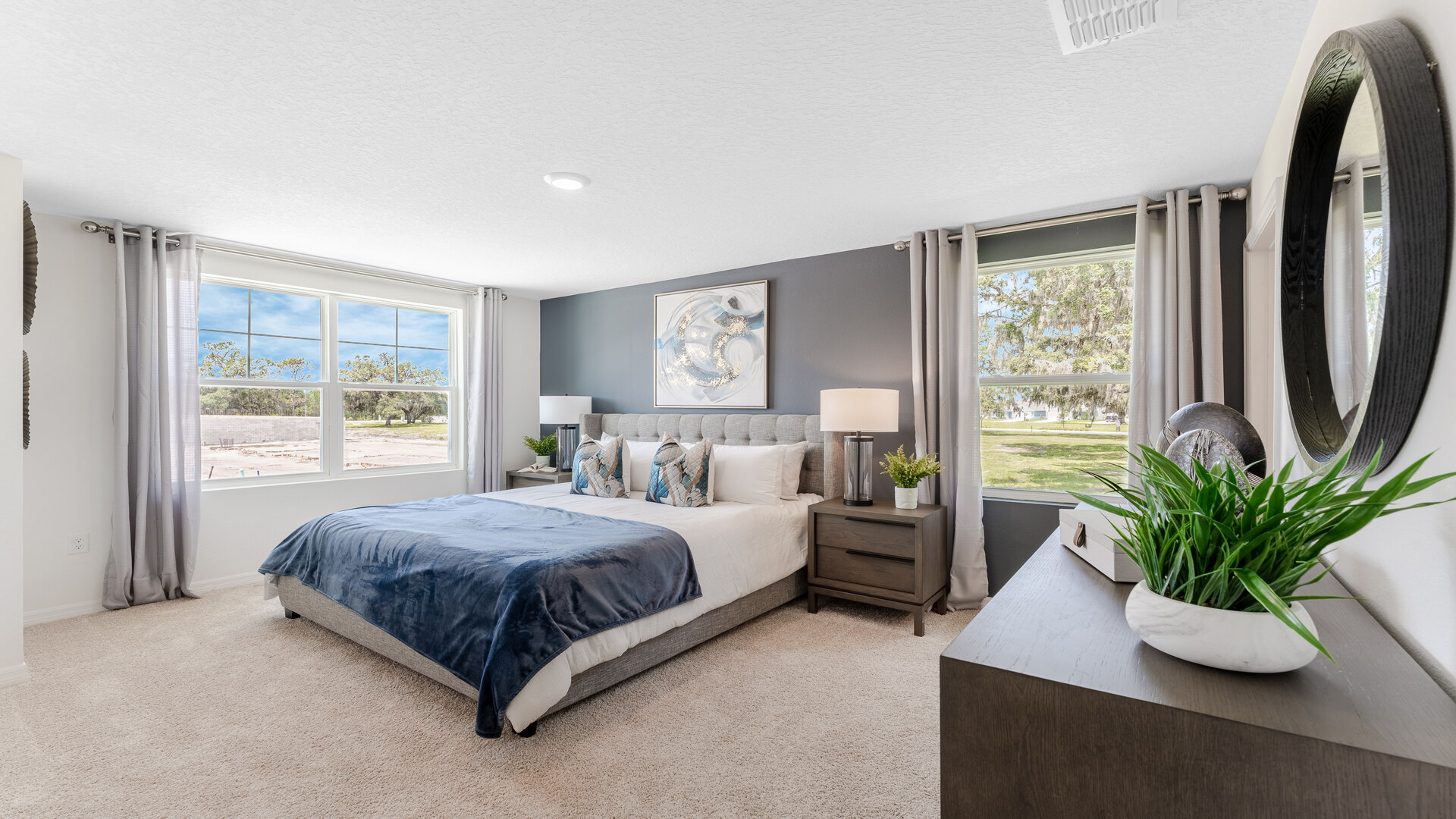 Spacious primary bedroom with king size bed, carpet flooring, natural lighting and a walk in closet.