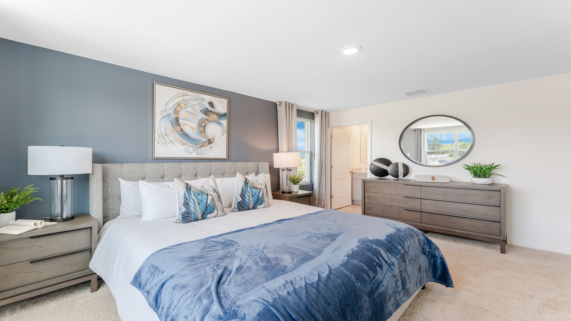 Spacious primary bedroom with king size bed, carpet flooring, natural lighting and a walk in closet.