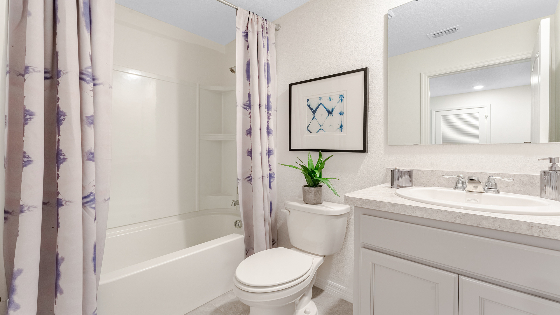 Modern bathroom with single bowl sink, granite vanity, wall mirror, cabinets and toilet.