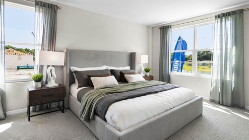 Spacious primary bedroom with king size bed, carpet flooring, natural lighting.