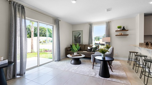 Living area with couch seating, sliding door backyard access, and natural lighting.