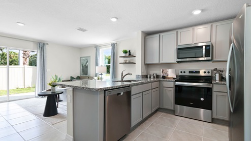 Kitchen with island seating, granite counters, spacious pantry and stainless steel appliances.