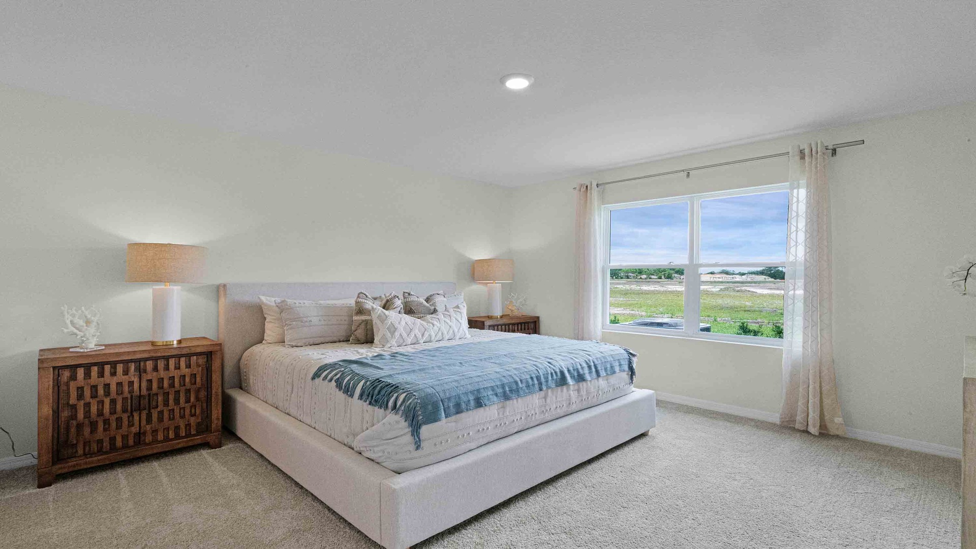 Spacious primary bedroom with king size bed, carpet flooring, natural lighting and a walk in closet.