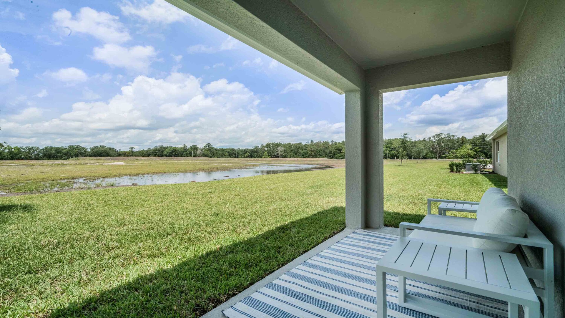 Rear of home with view of grassed backyard, porch seating and slider glass doors.