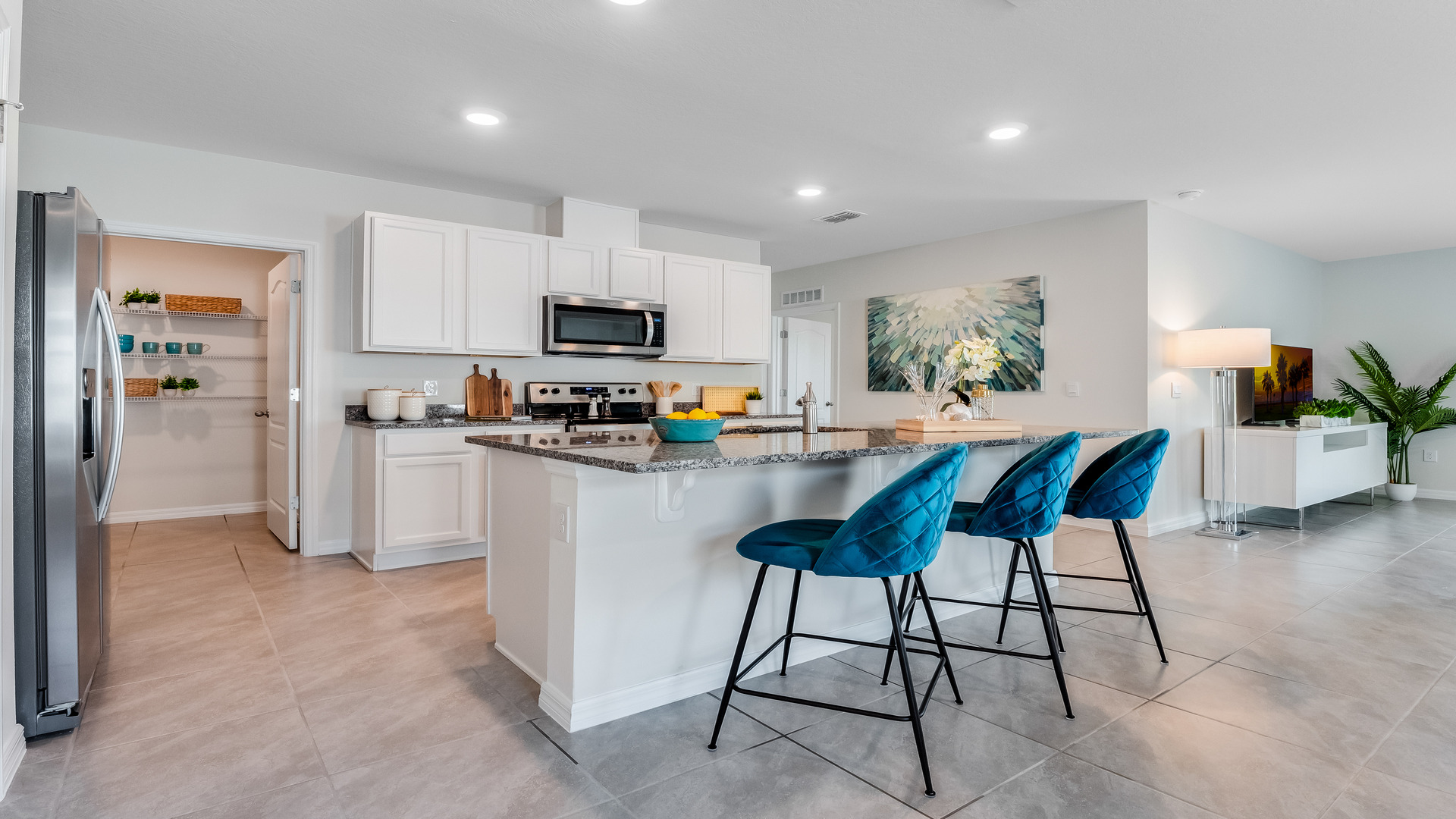 Kitchen with island seating, granite counters, spacious pantry and stainless-steel appliances.