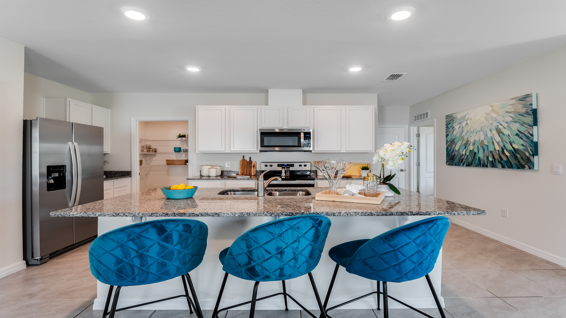 Kitchen with island seating, granite counters, spacious pantry and stainless-steel appliances.