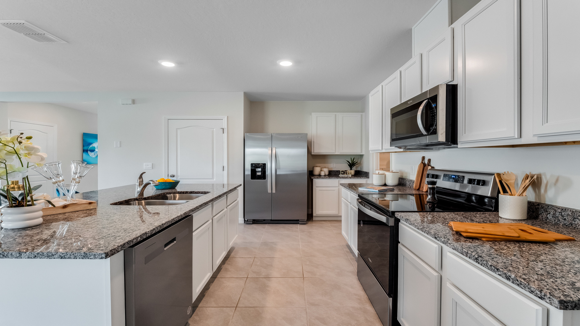 Kitchen with island seating, granite counters, spacious pantry and stainless-steel appliances.
