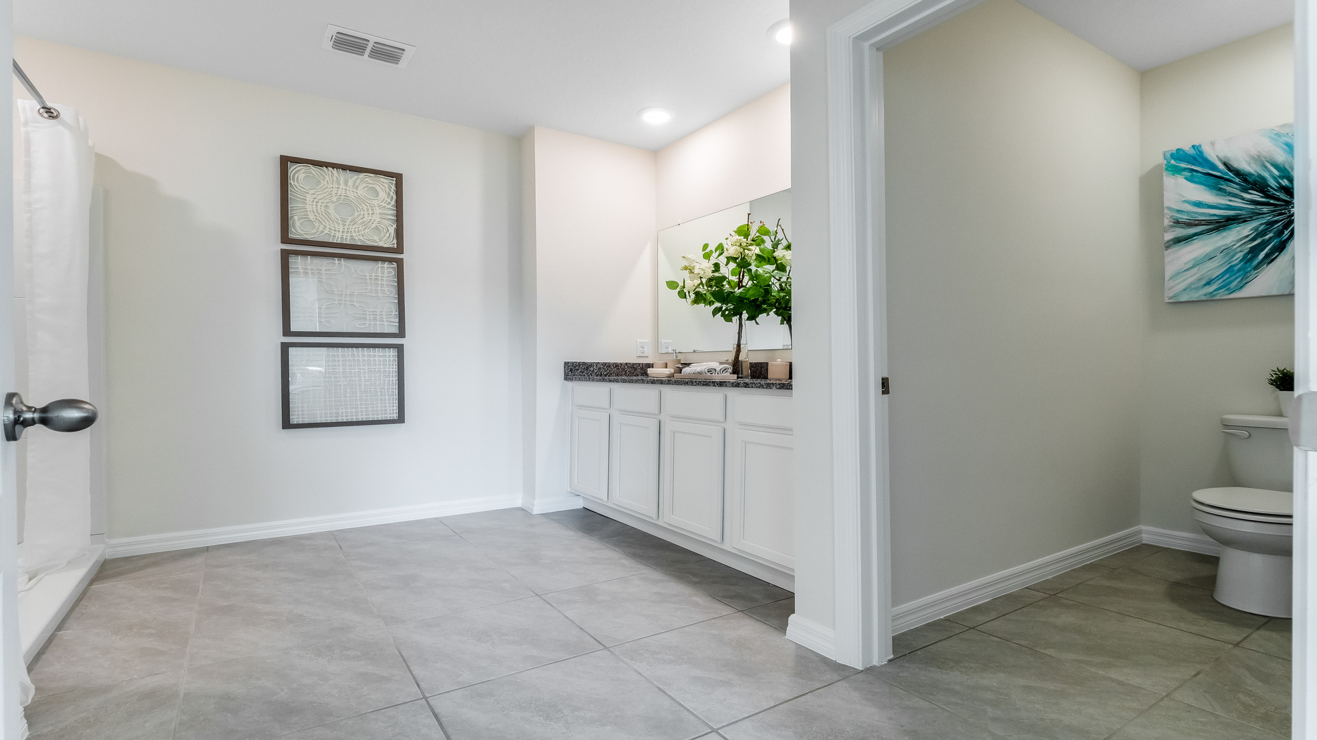 Modern bathroom with double vanity, large wall mirror, cabinets and granite countertops along with walk-in shower.