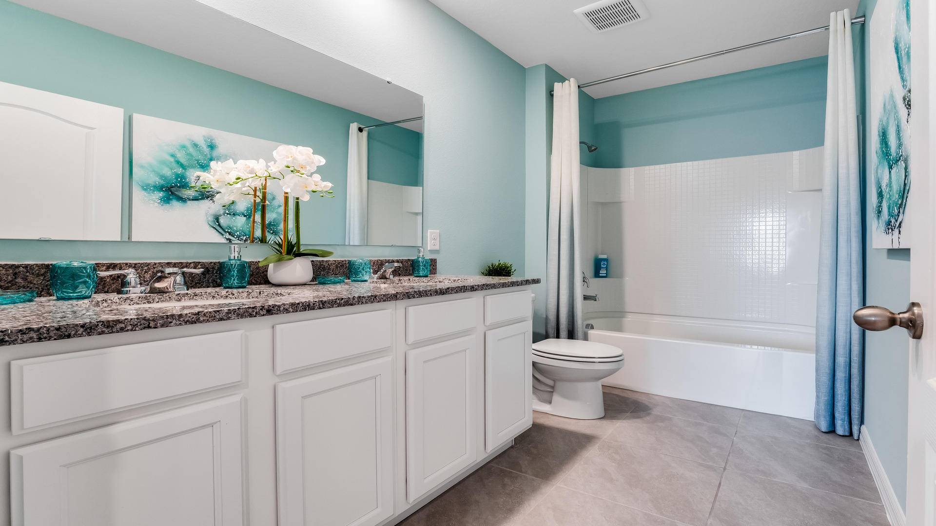 Modern bathroom with double vanity, large wall mirror, cabinets and granite countertops along with walk-in shower.