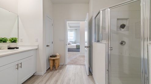 Modern bathroom with double vanity, large wall mirror, cabinets and granite countertops along with walk-in shower