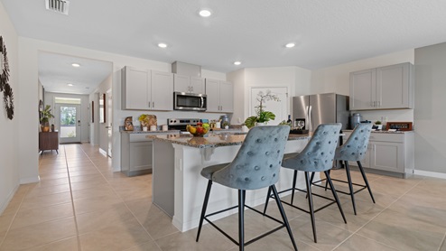Kitchen with island seating, granite counters, spacous pantry and stainless steel appliances.