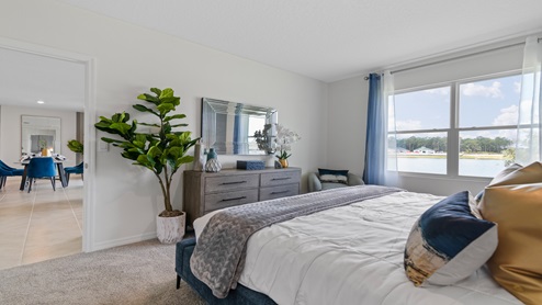 Spacious primary bedroom with king size bed, carpet flooring, natural lighting and a walk in closet.