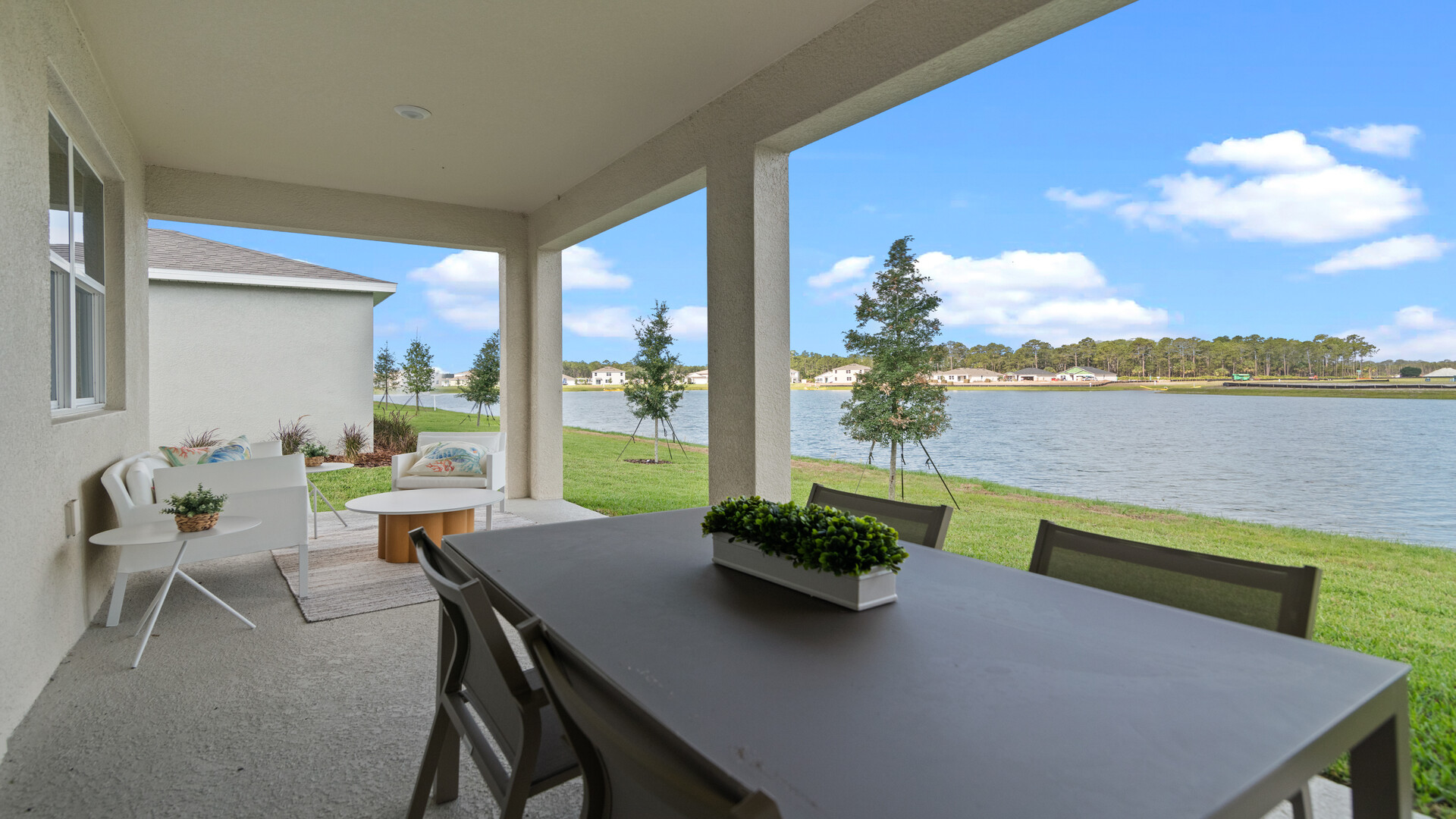 Rear of home with view of grassed backyard, porch seating and slider doors.