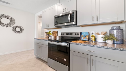 Kitchen with tall cabinetry, appliances, walk in pantry and tile flooring.
