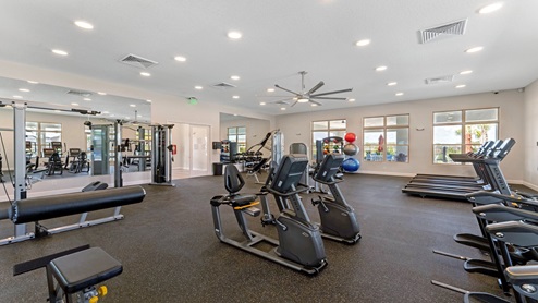 Gym facility with rubber mat flooring, mirror walls and a variety of equipment.