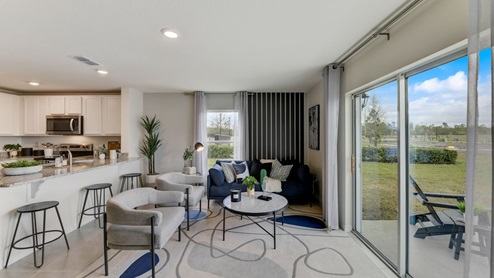Living room that fits chairs and a couch with sliding glass door for natural lighting.