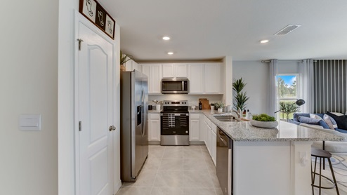 Kitchen with island seating, granite counters, spacious pantry and stainless-steel appliances.