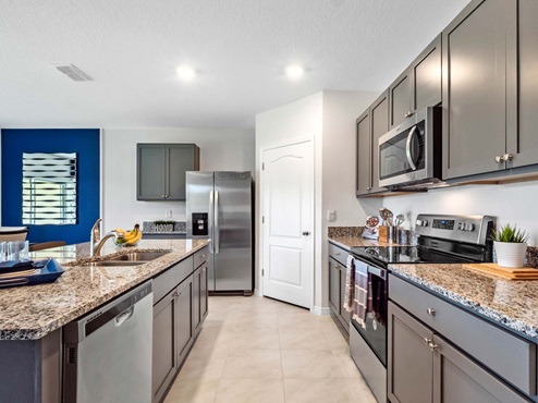 Kitchen with island seating, granite counters, spacious pantry and stainless-steel appliances.