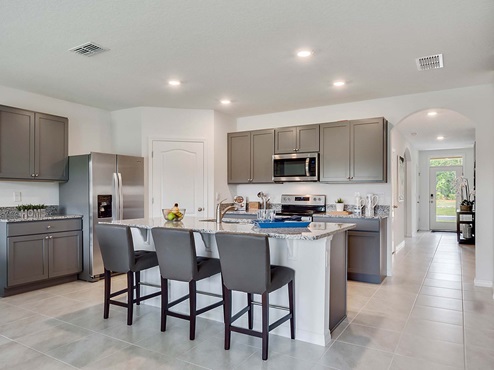 Kitchen with island seating, granite counters, spacious pantry and stainless-steel appliances.