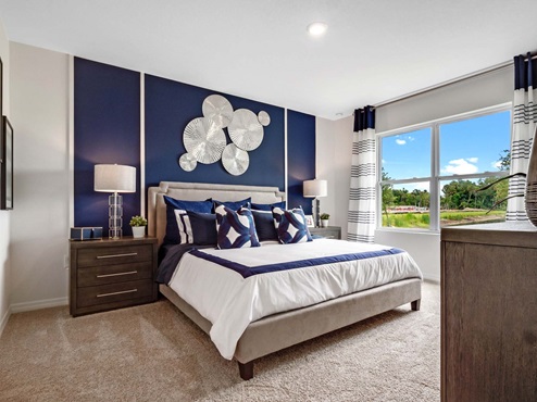 Spacious primary bedroom with king size bed, carpet flooring, natural lighting and a walk in closet.