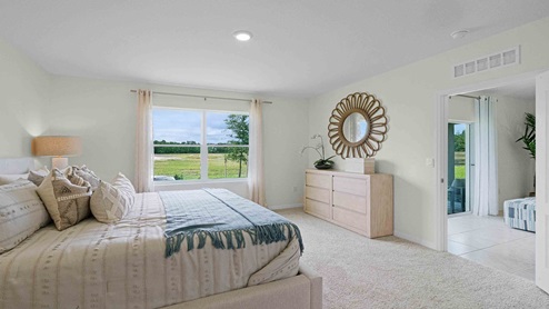 Spacious primary bedroom with king size bed, carpet flooring, natural lighting and a walk in closet.