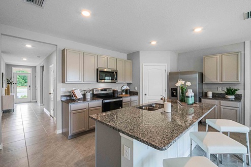 Kitchen with tall cabinetry, appliances, walk in pantry and tile flooring.