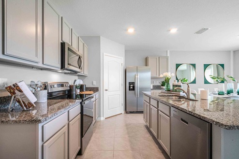 Kitchen with tall cabinetry, appliances, walk in pantry and tile flooring.