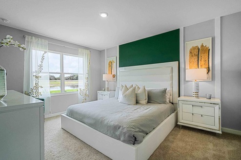 Spacious primary bedroom with king size bed, carpet flooring, natural lighting and a walk in closet.