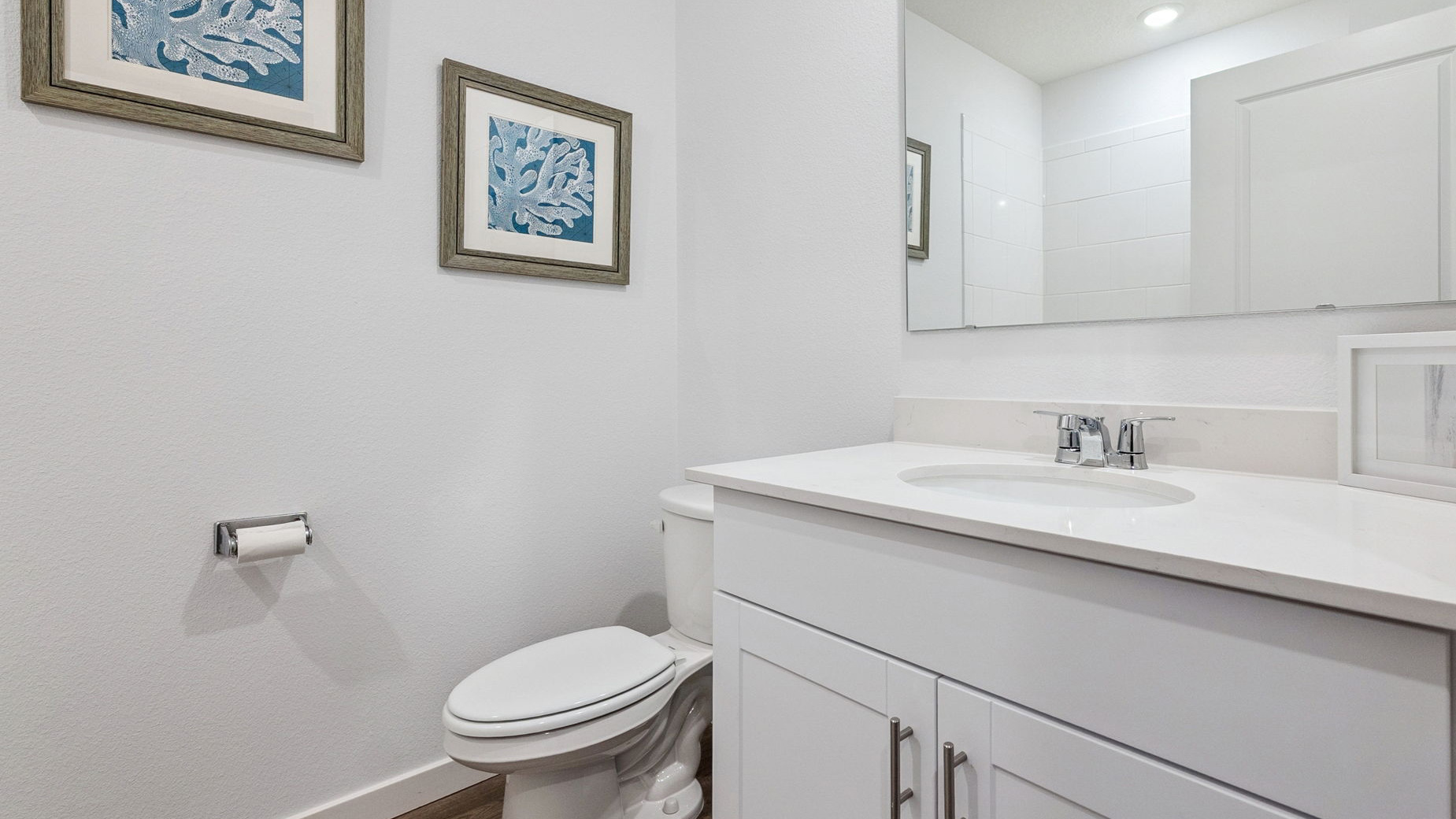 Modern bathroom with double vanity, large wall mirror, cabinets and quartz countertops showing access to master bedroom.