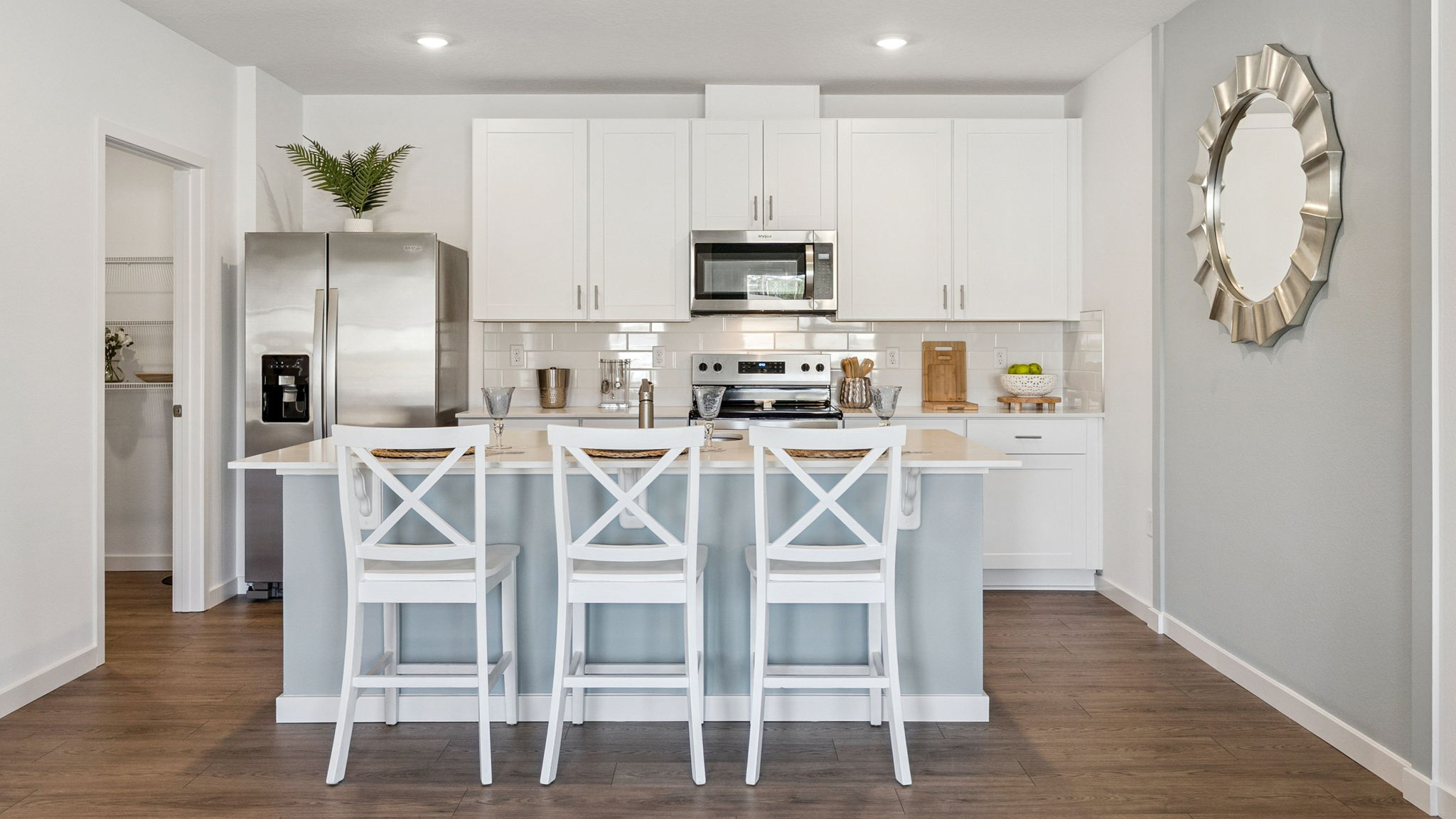 Kitchen with island seating, quartz counters, spacous pantry and stainless steel appliances.