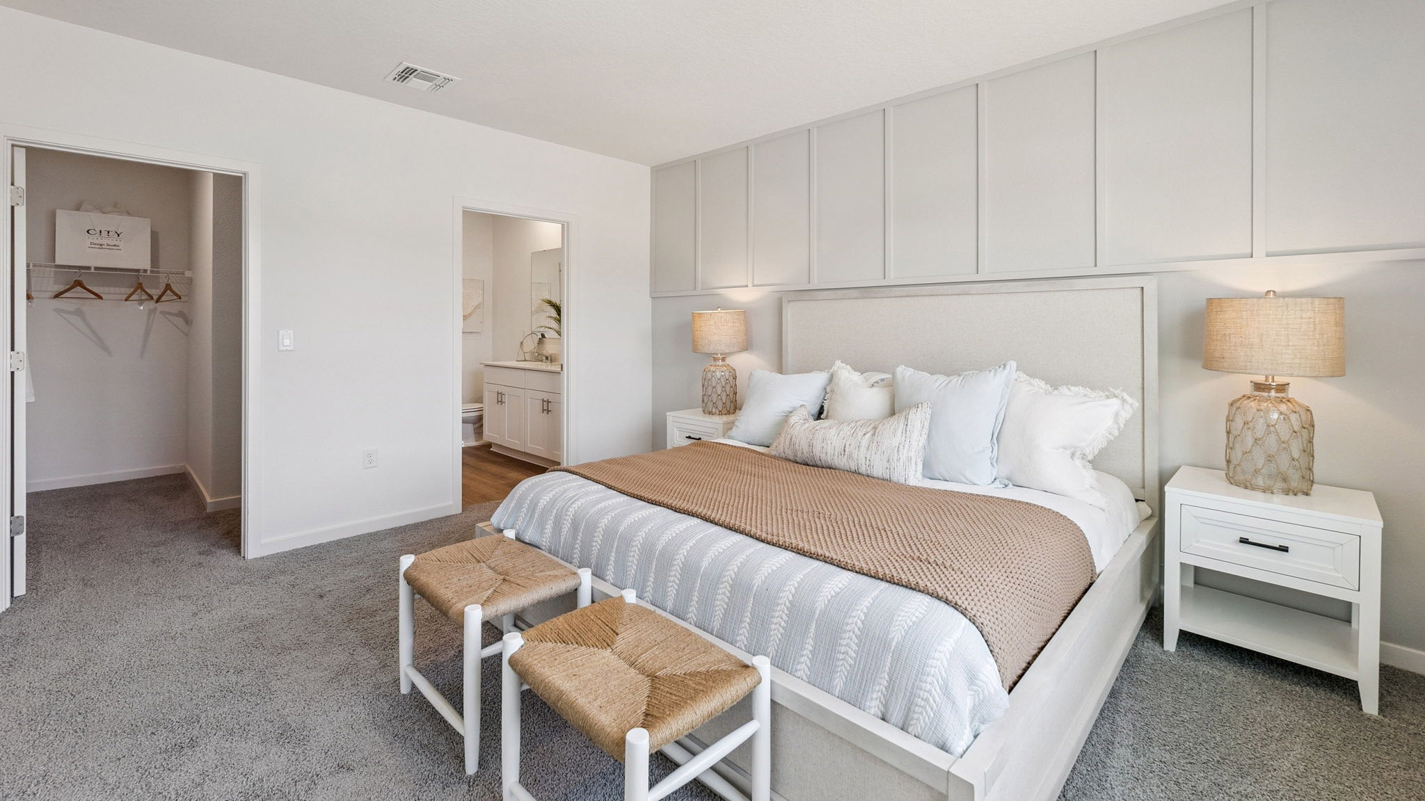 Spacious primary bedroom with king size bed, carpet flooring, natural lighting.