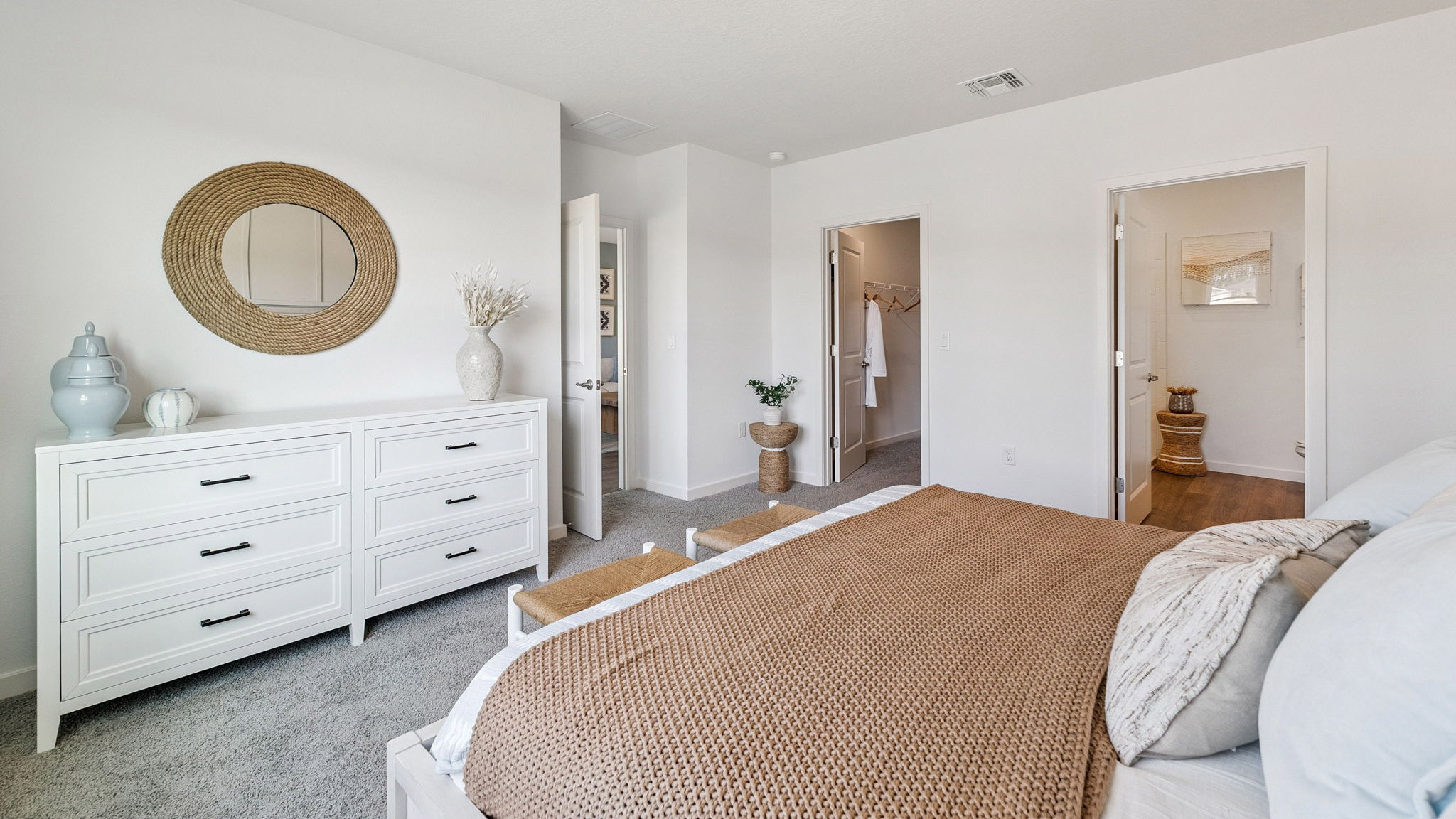 Spacious primary bedroom with king size bed, carpet flooring, natural lighting.