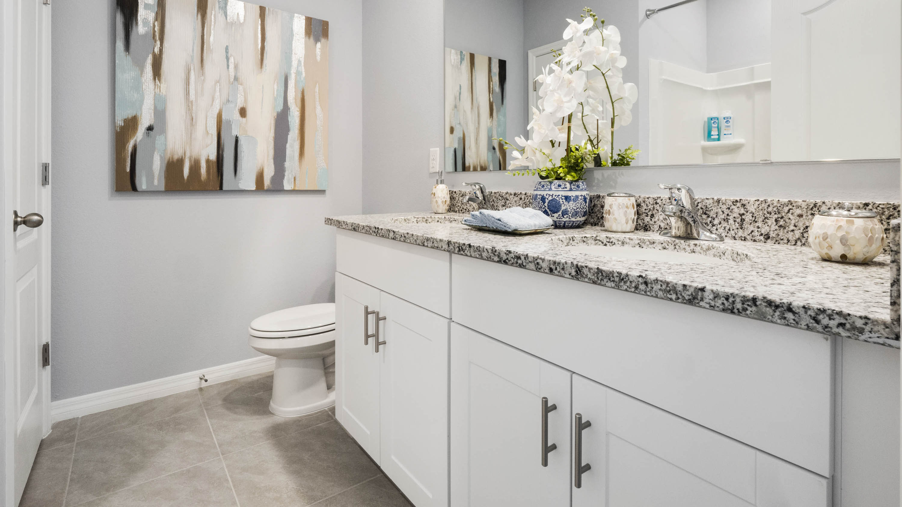Modern bathroom with single vanity, large wall mirror, cabinets and quartz countertops