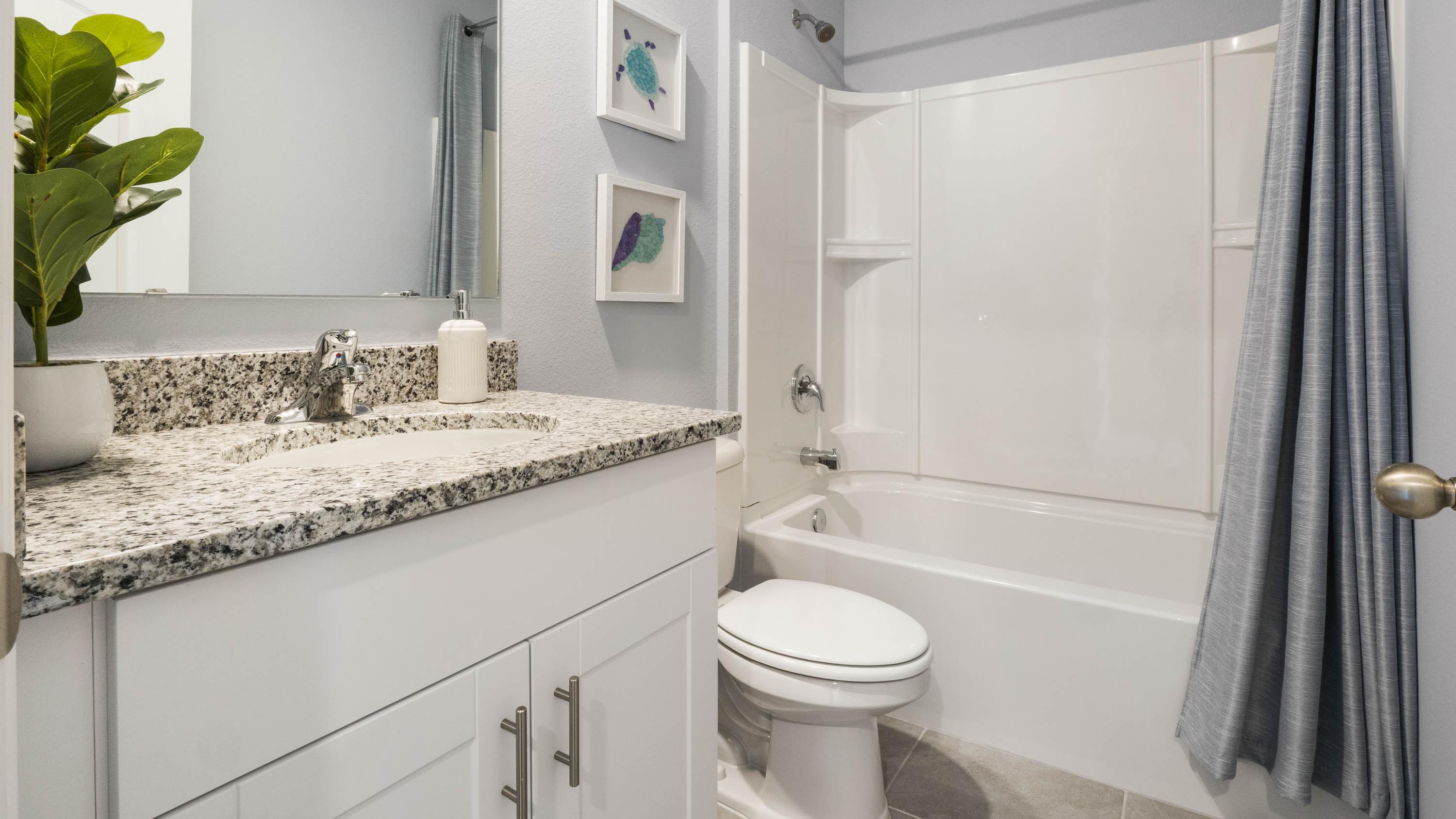 Modern bathroom with single vanity, large wall mirror, cabinets and quartz countertops