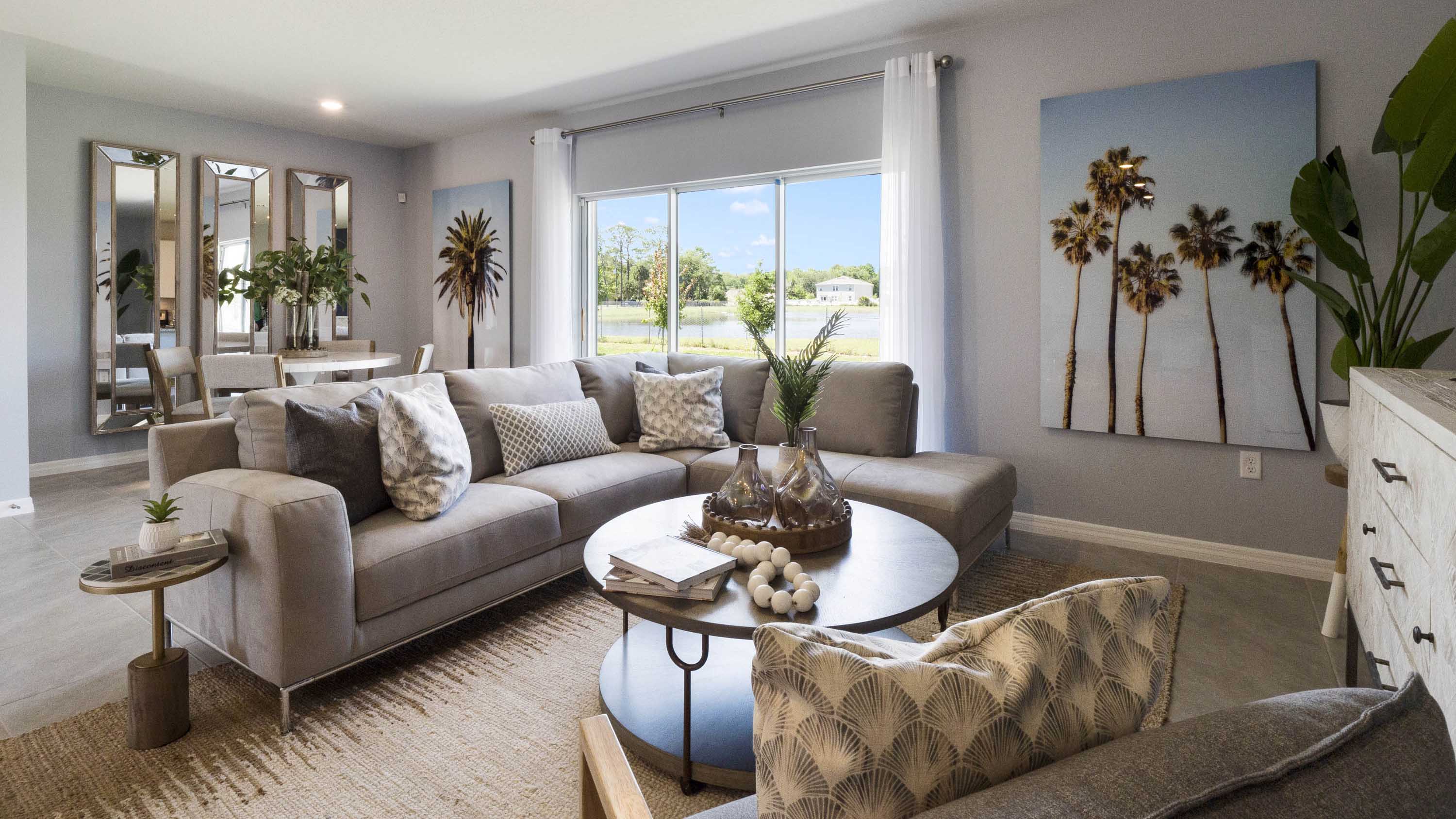 Living area with couch seating, entertainment system and natural lighting overseeing dining room table