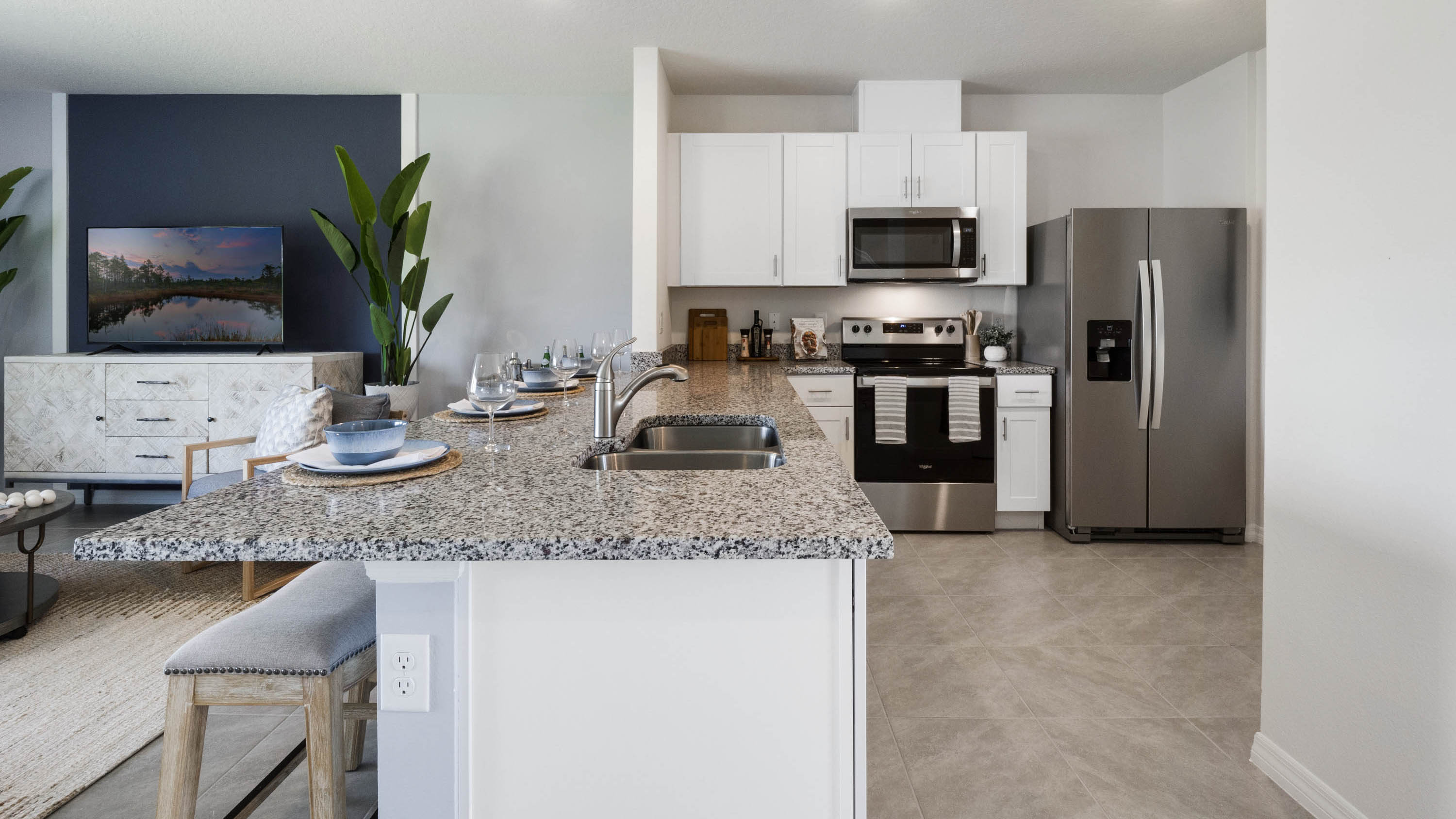 Kitchen with island seating, quartz counters, spacious pantry and stainless steel appliances.