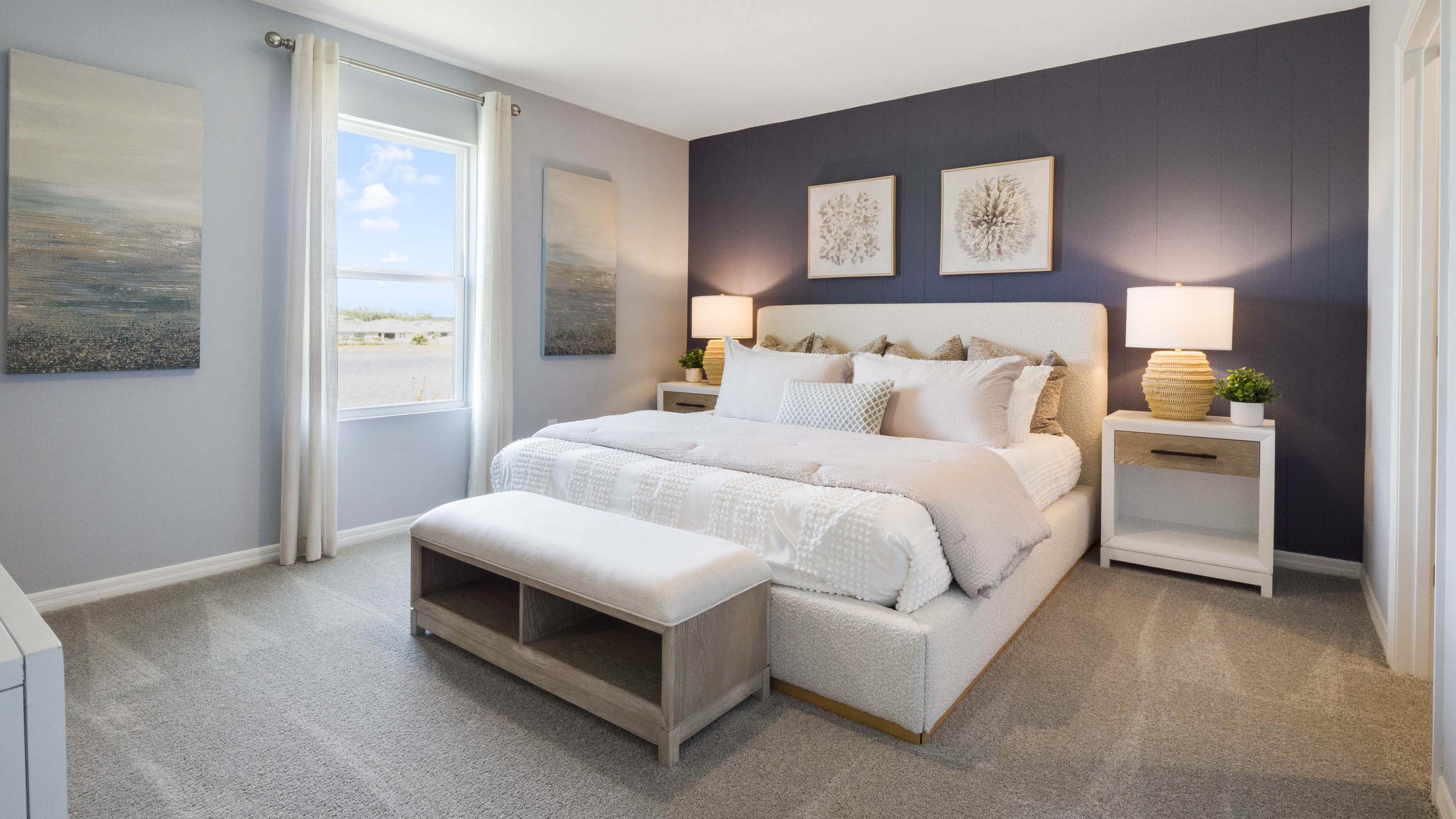 Spacious primary bedroom with king size bed, carpet flooring, natural lighting.