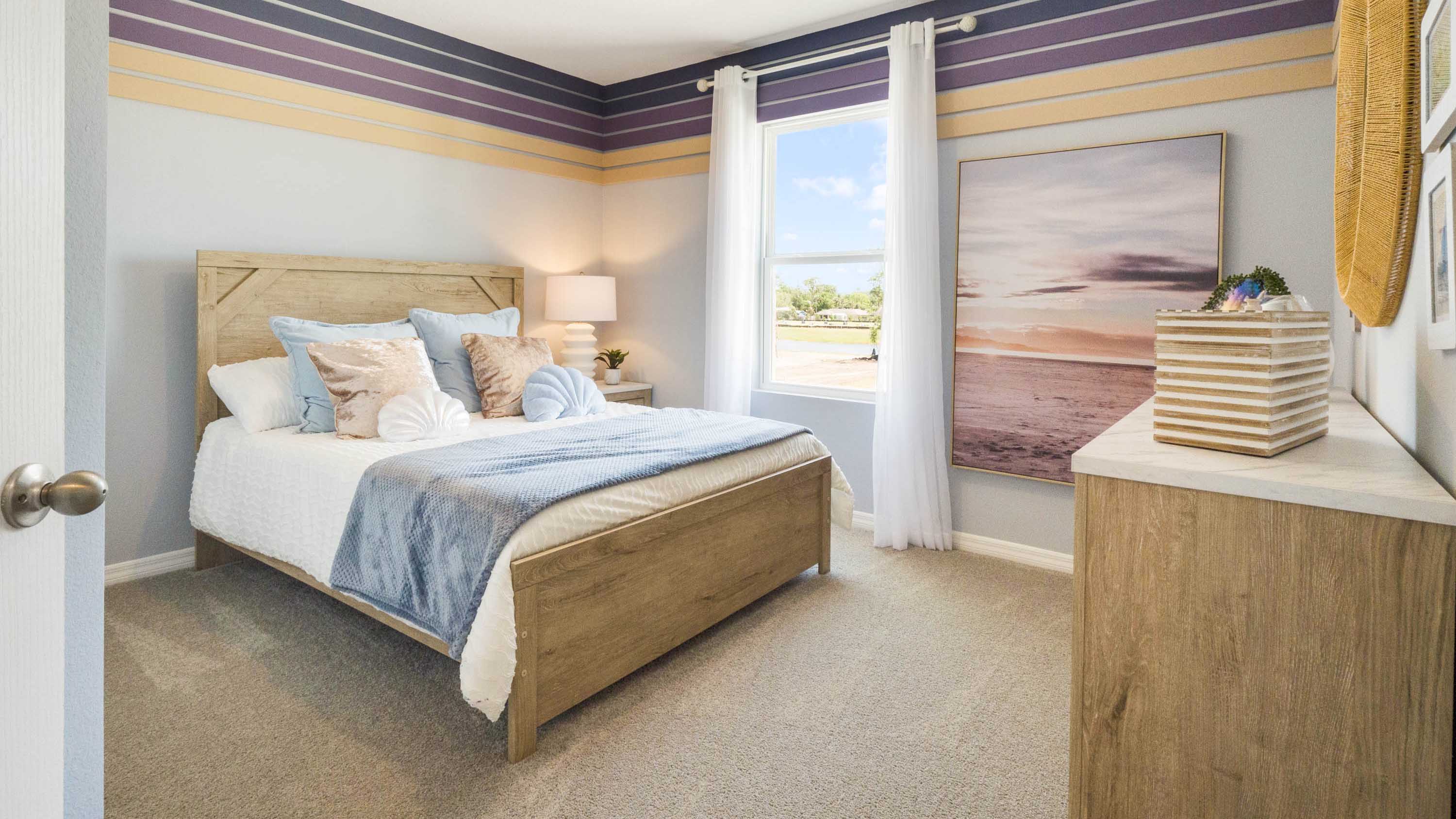 Spacious primary bedroom with king size bed, carpet flooring, natural lighting.