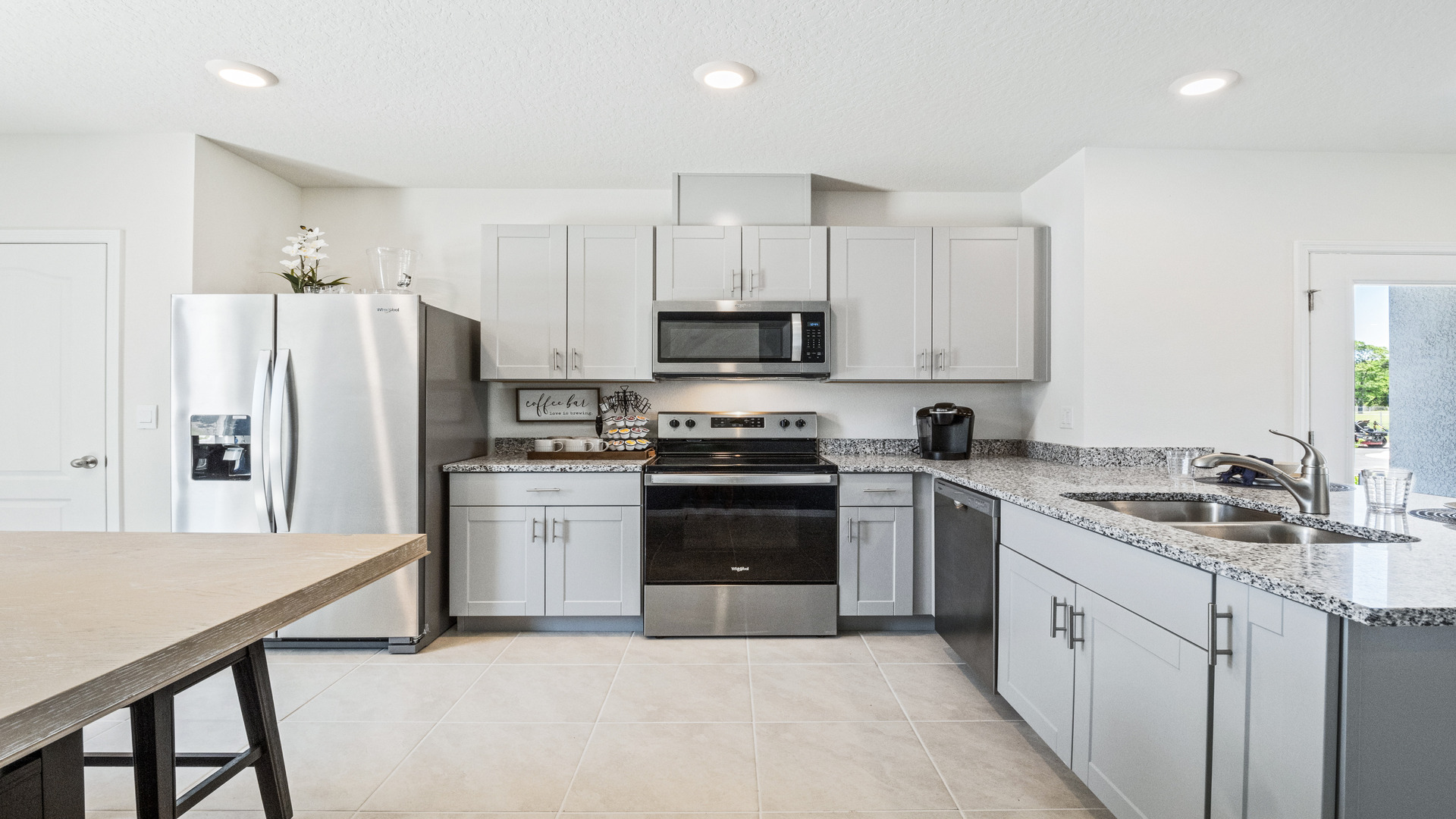 Kitchen with island seating, quartz counters, spacious pantry and stainless steel appliances.