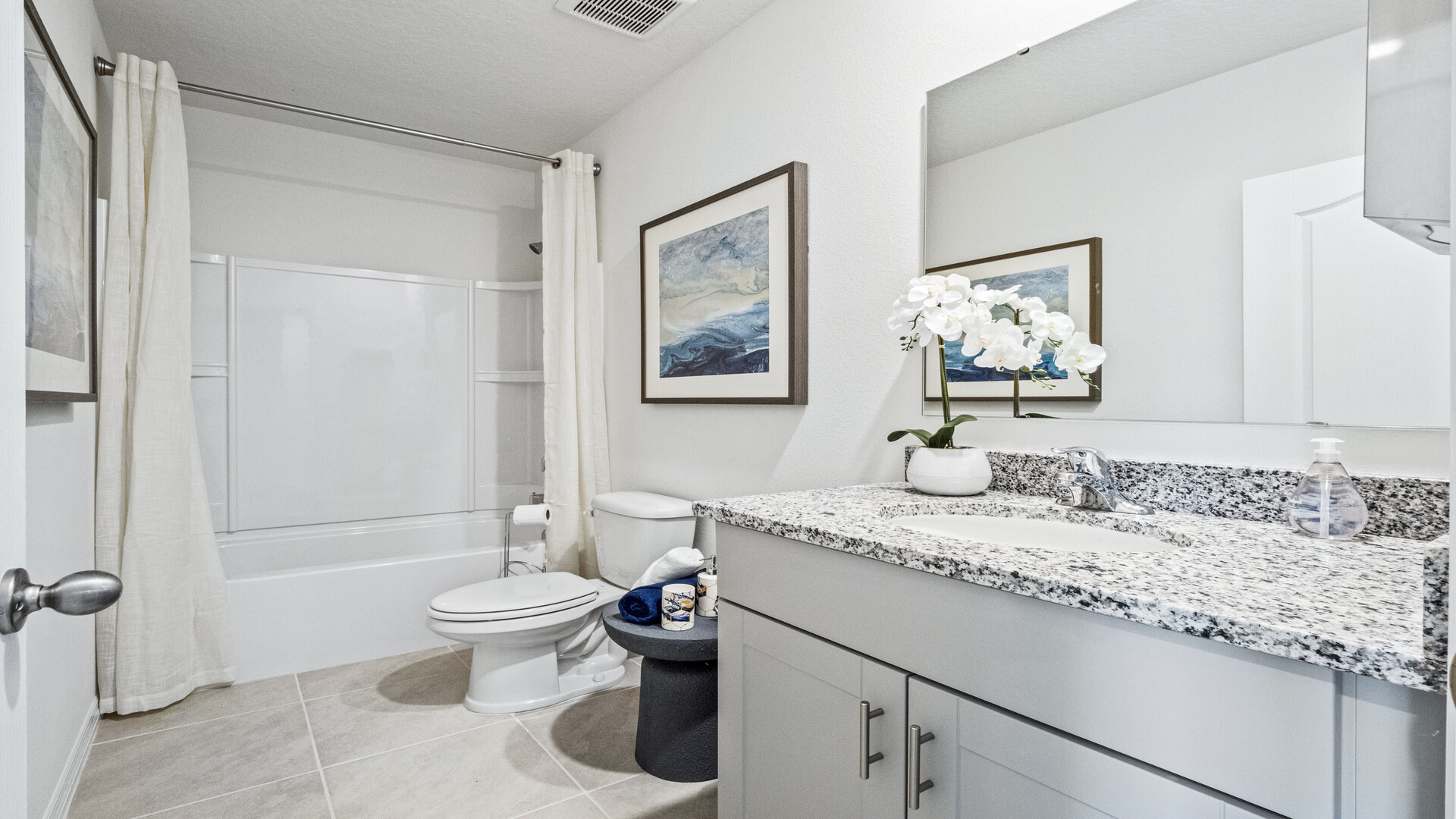 Modern bathroom with single vanity, large wall mirror, cabinets and quartz countertops