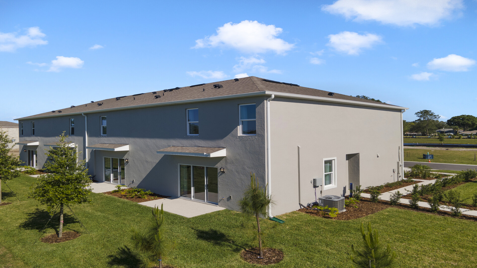 Rear of home with view of grassed backyard, porch seating and slider glass doors.