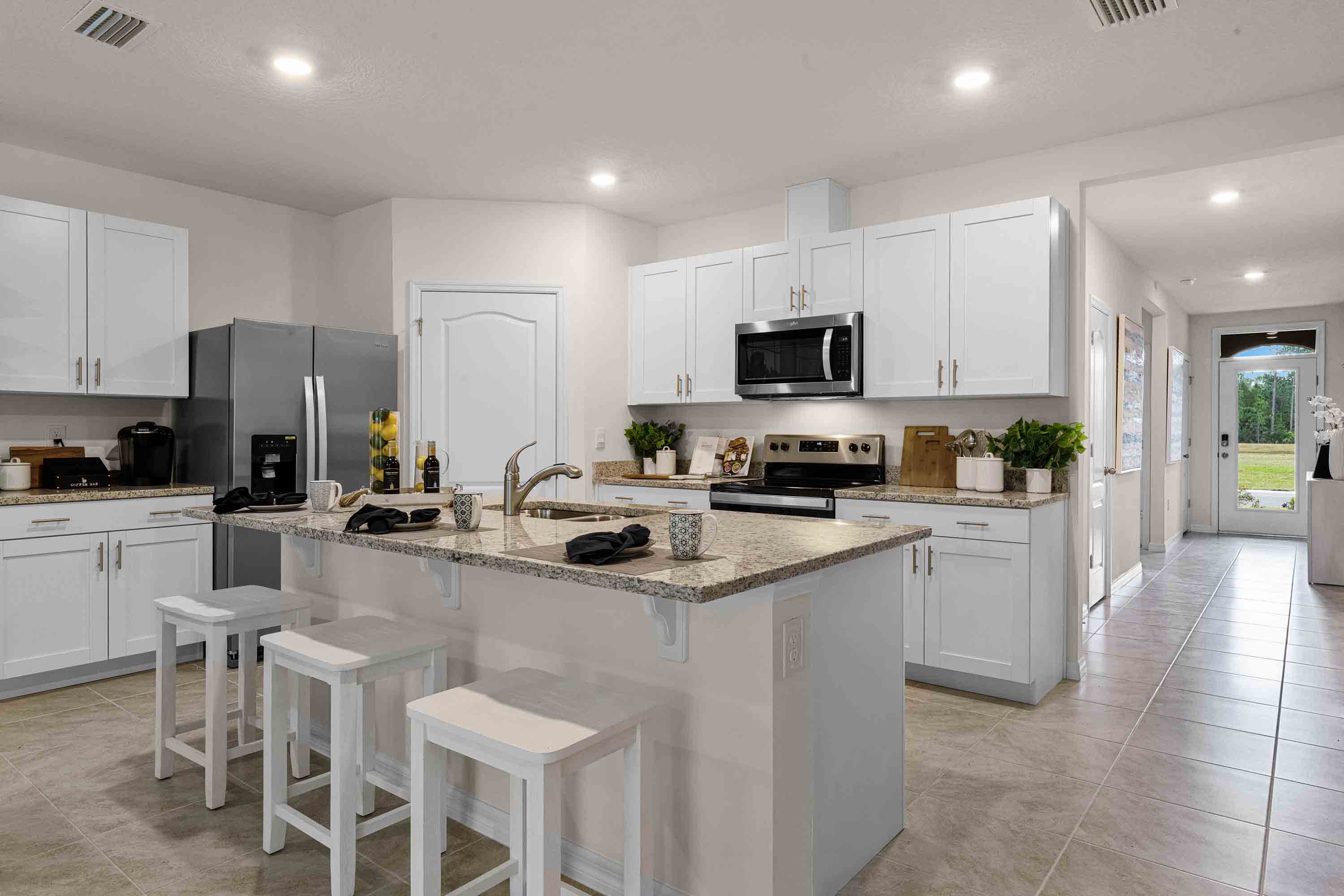 Kitchen with island seating, granite counters, spacious pantry and stainless-steel appliances.