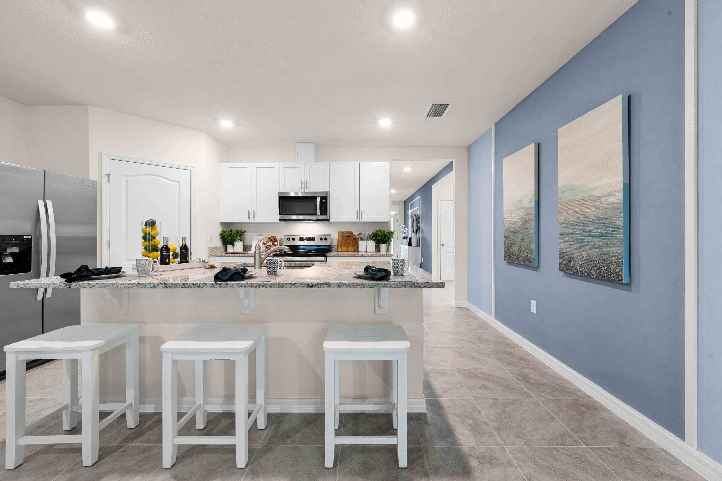 Kitchen with island seating, granite counters, spacious pantry and stainless-steel appliances.