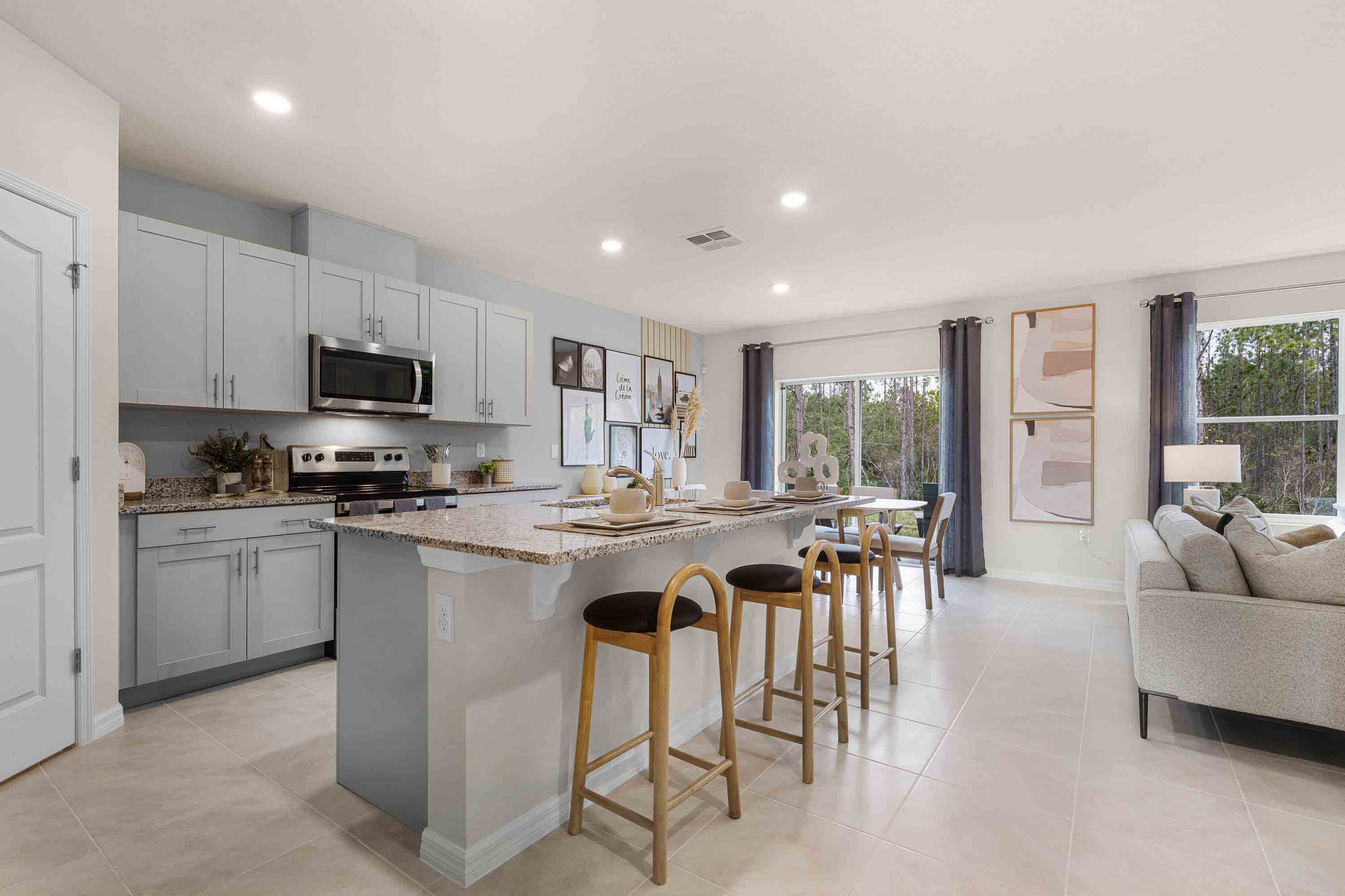 Kitchen with island seating, granite counters, spacious pantry and stainless-steel appliances.