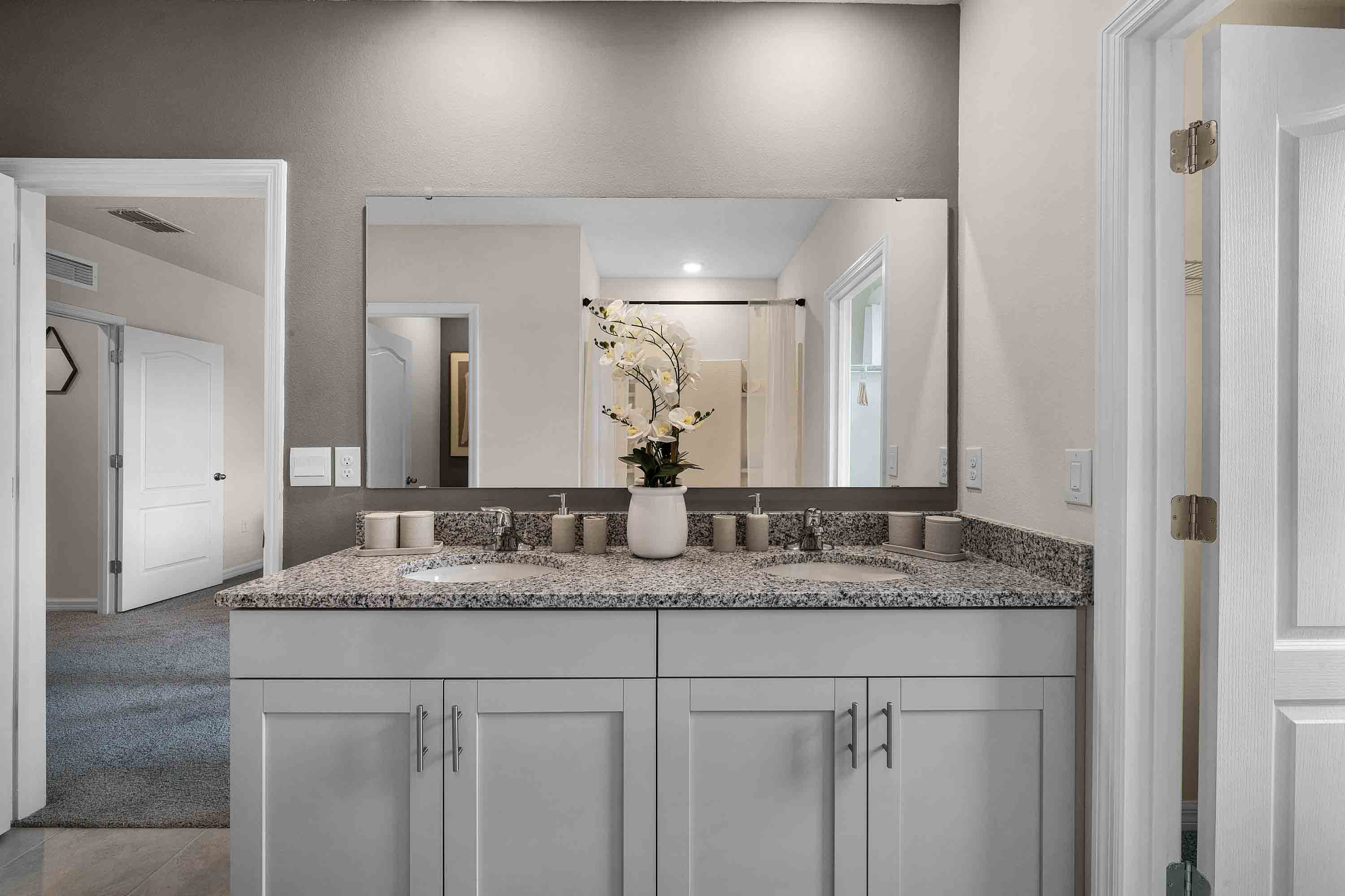 Modern bathroom with double vanity sinks, large wall mirror, cabinets and granite countertops.
